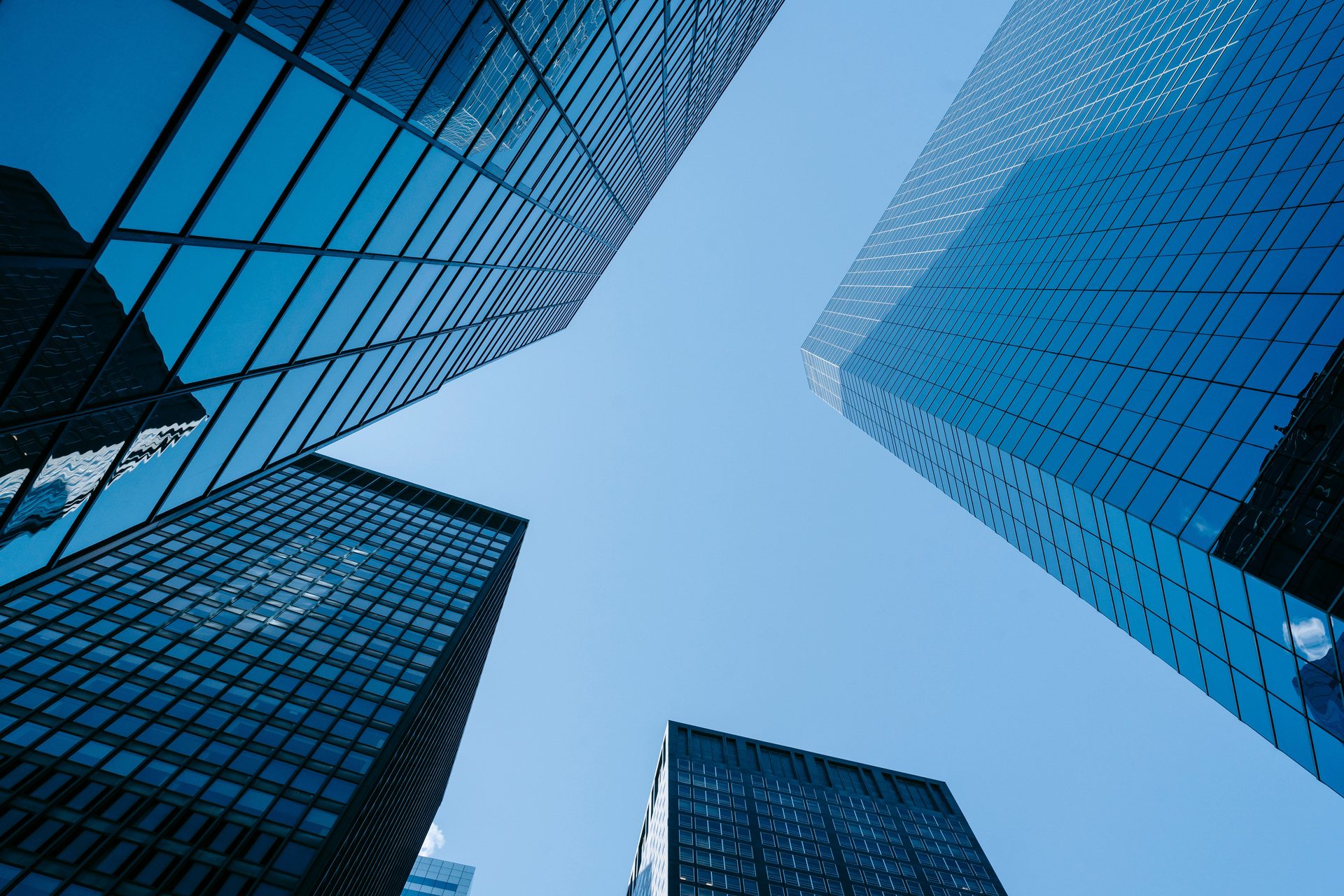 Low angle view of tall glass office skyscrapers against a clear blue sky